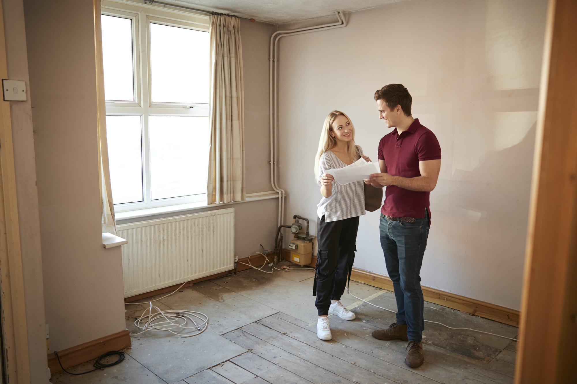 couple-buying-house-for-first-time-looking-at-house-survey-in-room-to-be-renovated.jpg